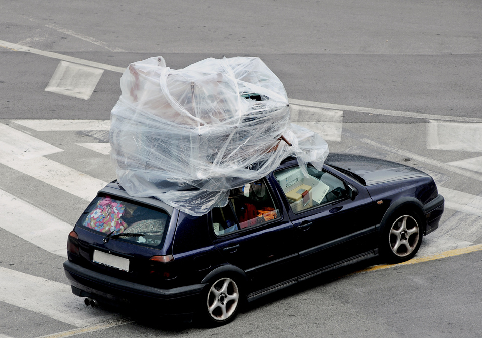 A car stuffed full of bags, crates, etc. Wrapped furniture on the roof. As an exaggerated picture for a fully loaded car during the holiday season.